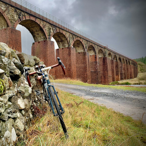 Bike leaning against a stone wall with the Big Water of Fleet viaduct in the background